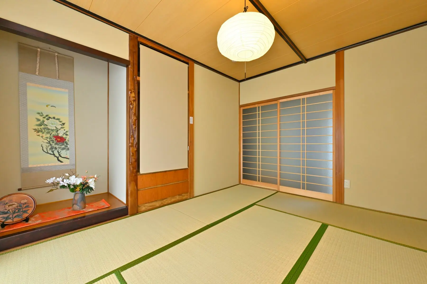 和室(一) — 生成りの壁。掛け軸と、白い提灯の照明。
